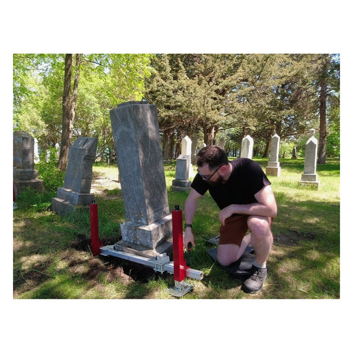 Installer kneeling beside a monument with Tombstone Jack lift feet in place
